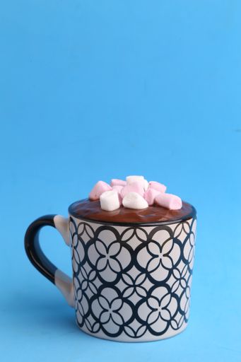A close up shot of a delicious hot drink with chocolate and marshmallows on top