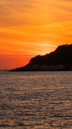 A vertical shot of an orange sunset over a cliff in Ulcinj, Montenegro