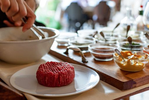 A closeup shot of chef making steak tartare on trolley with spices and ingredients