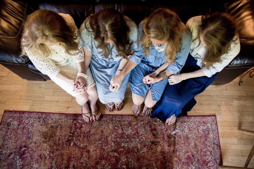 An overhead shot of four female sitting and holding their hands while praying