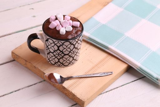 A close up shot of a delicious hot drink with chocolate and marshmallows on top