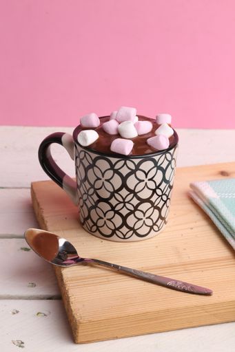 A close up shot of a delicious hot drink with chocolate and marshmallows on top