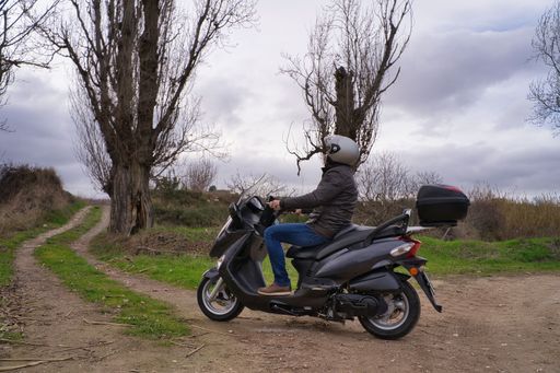 A Hispanic man riding scooter in a rural field