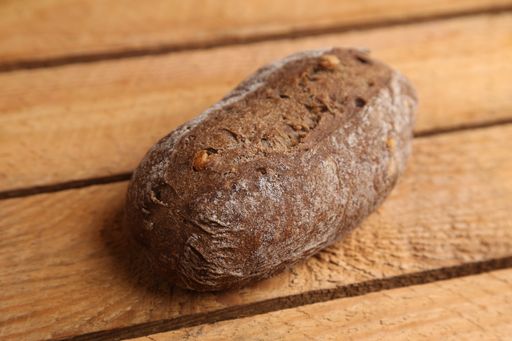 A closeup shot of homemade brown bread with nut pieces on a wooden surface
