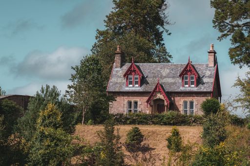 A lovely scottish-style house in a forested area under the sunlight