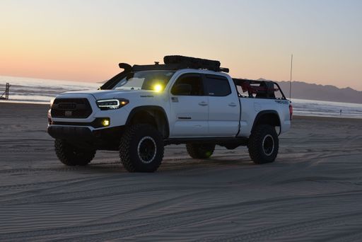 A Toyota Tacoma parked at the beach at soft sunset