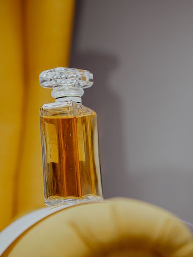 A vertical shot of an aesthetic clear perfume bottle with gold substance