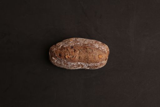 A top view of a loaf of dry brown bread on a black surface