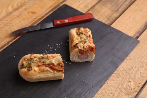 Two cut pieces of a delicious crispy hot dog on a black wooden board