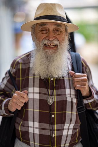 A beautiful shot of a bearded old man with hat smiling at the camera