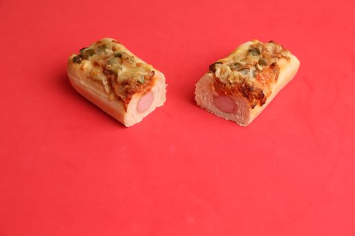 A closeup shot of two pieces of pizza loafs with sausage on a red background
