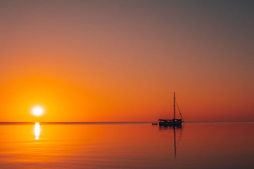 A beautiful view of a sailing boat silhouette in the ocean at sunset in Southern Belize.