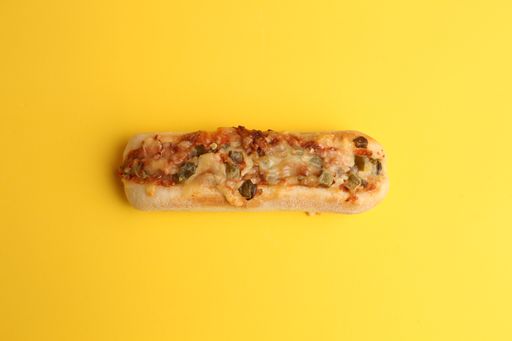 A high angle shot of a sandwich with grilled cheese with vegetables on a yellow surface