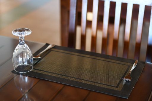 A Closeup shot of a wooden decorated dining table with a glass cup with blur chair