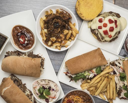 A high angle shot of plates of different food, sandwiches and french fries