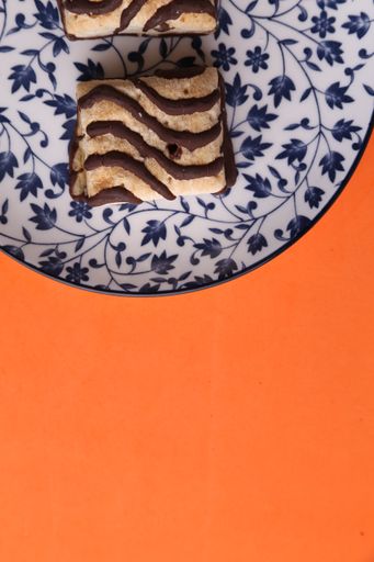 A vertical high angle shot of a plate of homemade cookies isolated on an orange surface