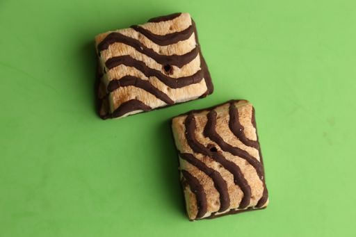 An overhead shot of tasty biscuits with chocolate on top on a green background
