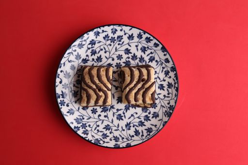 A top view of small chocolate biscuits on a plate on a red surface