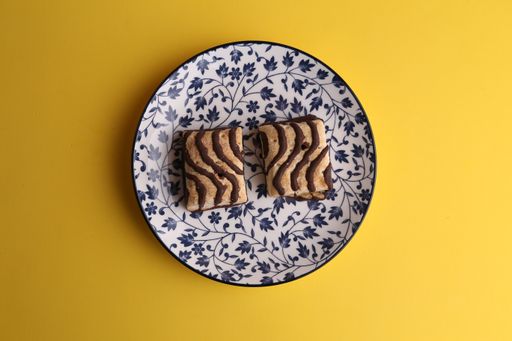 An overhead shot of delicious square biscuits with chocolate cream on a decorative plate