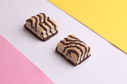 A closeup shot of delicious chocolate cake pieces on a pink and yellow background