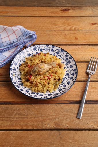 A vertical shot of a dish with rice, chicken and peppers on wooden background