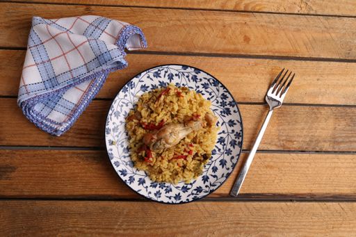 A top view of a plate of curried rice ready to be eaten and a towel on the side on a wooden table