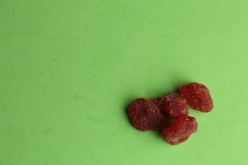 A high angle shot of some dried plums isolated on a green surface