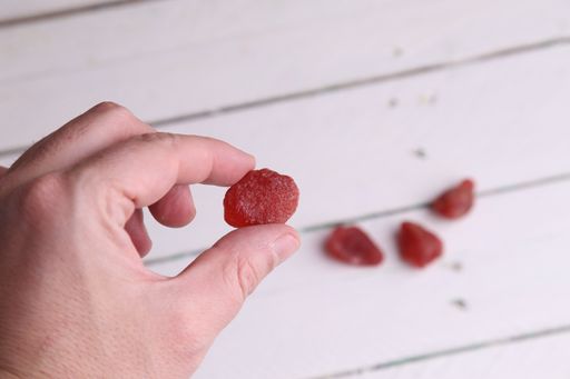 A selective focus shot of a male hand holding a sweet red candy