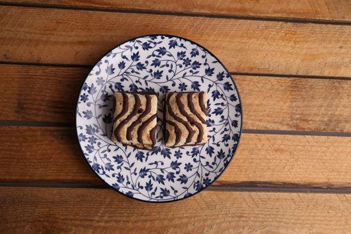A top view of a decorative plate with chocolate glazed biscuits on wooden surface