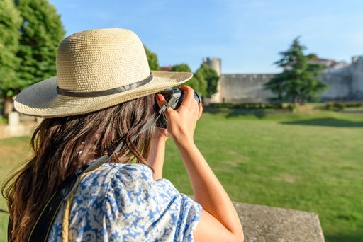 A back view of Caucasian woman taking photo of village through camera