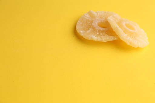 A high angle shot of two slices of dried pineapples isolated on a yellow surface