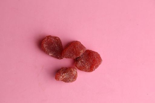 A top view of strawberry candies on a pink surface under the lights