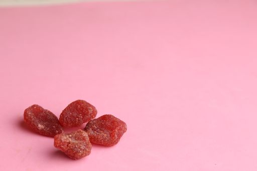 A high angle shot of some dried plums isolated on a pink surface