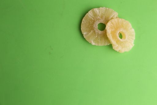 A high angle shot of two slices of dried pineapples isolated on a green surface