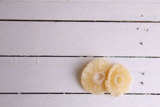 A high angle shot of two slices of dried pineapples isolated on a white wooden surface