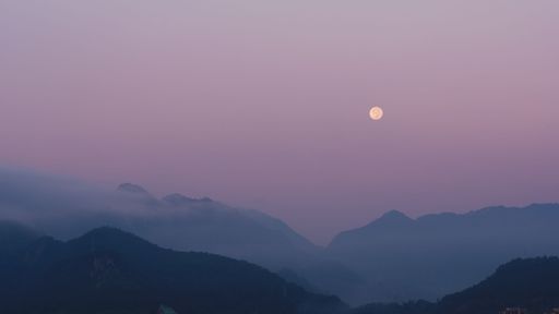 A scenic view of clouds covering the evergreen mountains against a mesmerizing sky