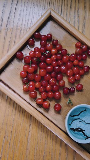 A vertical top view of delicious cherries on a wooden board on the table