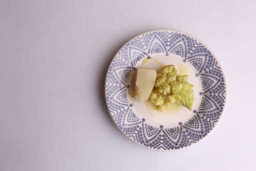 A top view of a plate with a romanesco broccoli and potato dish isolated on a red surface