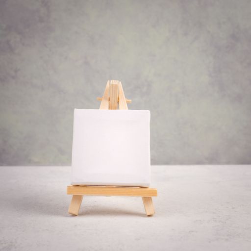 Easel with blank white canvas in front of a gray textured background, frame to add paintings and pictures