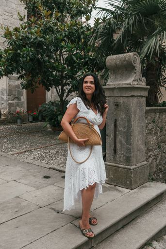 A Caucasian woman wearing white drees standing in street of old town