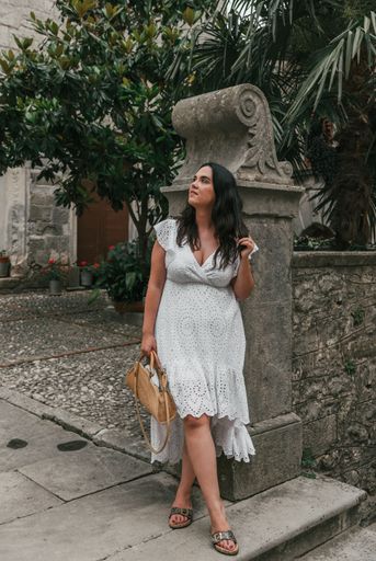 A Caucasian woman wearing white drees standing in street of old town