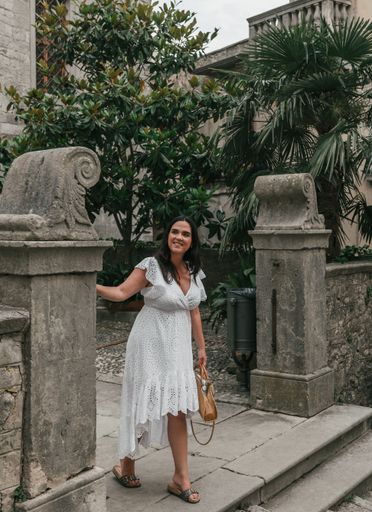 A Caucasian woman wearing white drees standing in street of old town