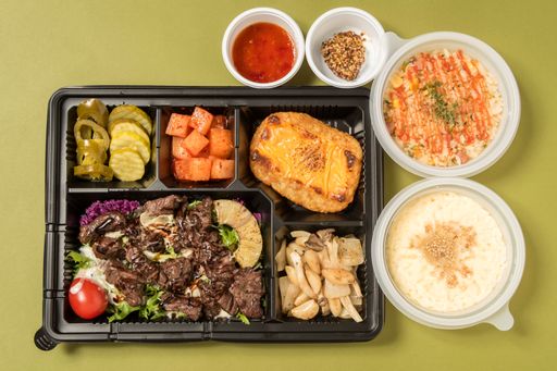 a flat lay of a tray with a variety of Asian food isolated on a green background.