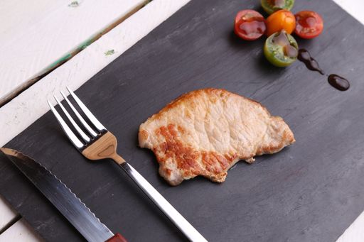 A closeup shot of a delicious steak with grilled cherry tomatoes on a black board