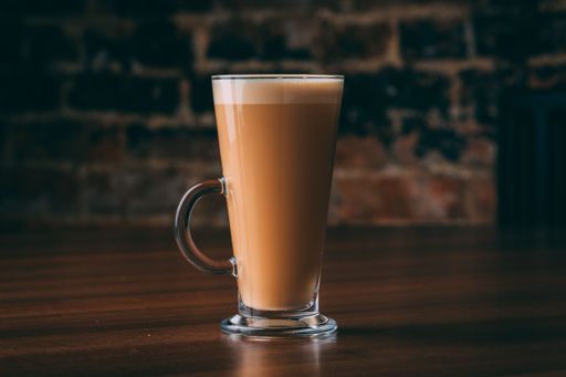 A closeup of iced coffee in a glass on a wooden table