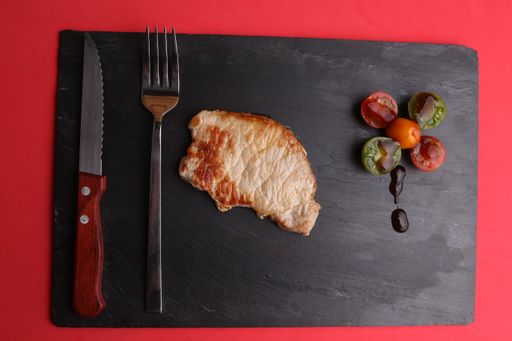 A closeup shot of a delicious steak with grilled cherry tomatoes on a black board