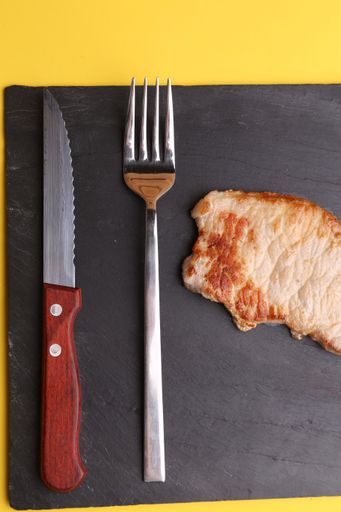A closeup shot of a delicious homemade steak with a fork and a knife by its side