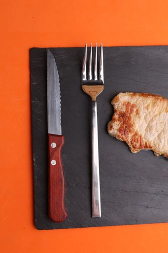 A closeup of the delicious steak on a black board on an orange background
