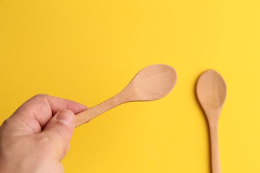 A top view shot of hand of a man holding a wooden spoon isolated on a yellow background