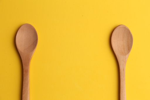 A closeup shot of two wooden spoons on a yellow background